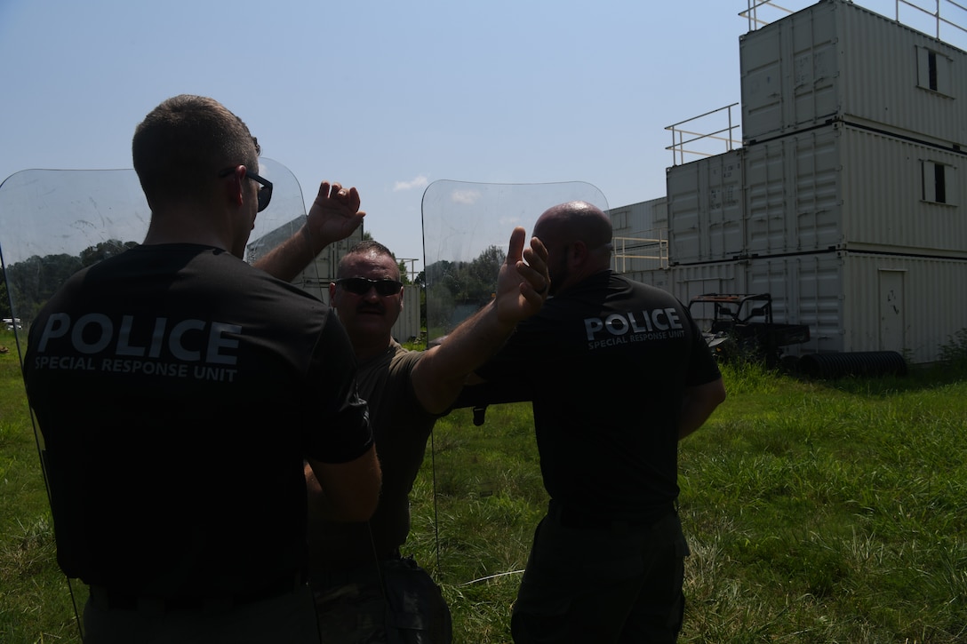 Airman trying to push through two police officers with shields during training.