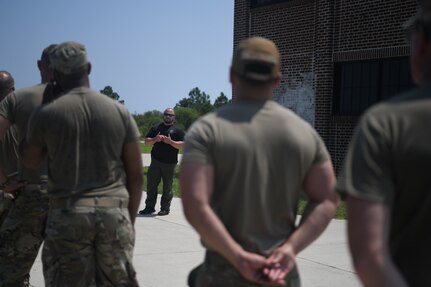 Police officer speaking to group of Airmen during training.