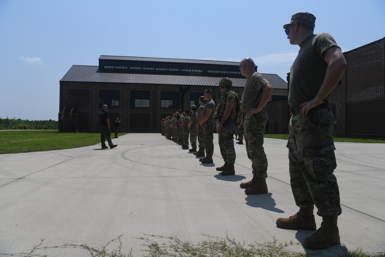 Two police officers talking to a line of Airmen.