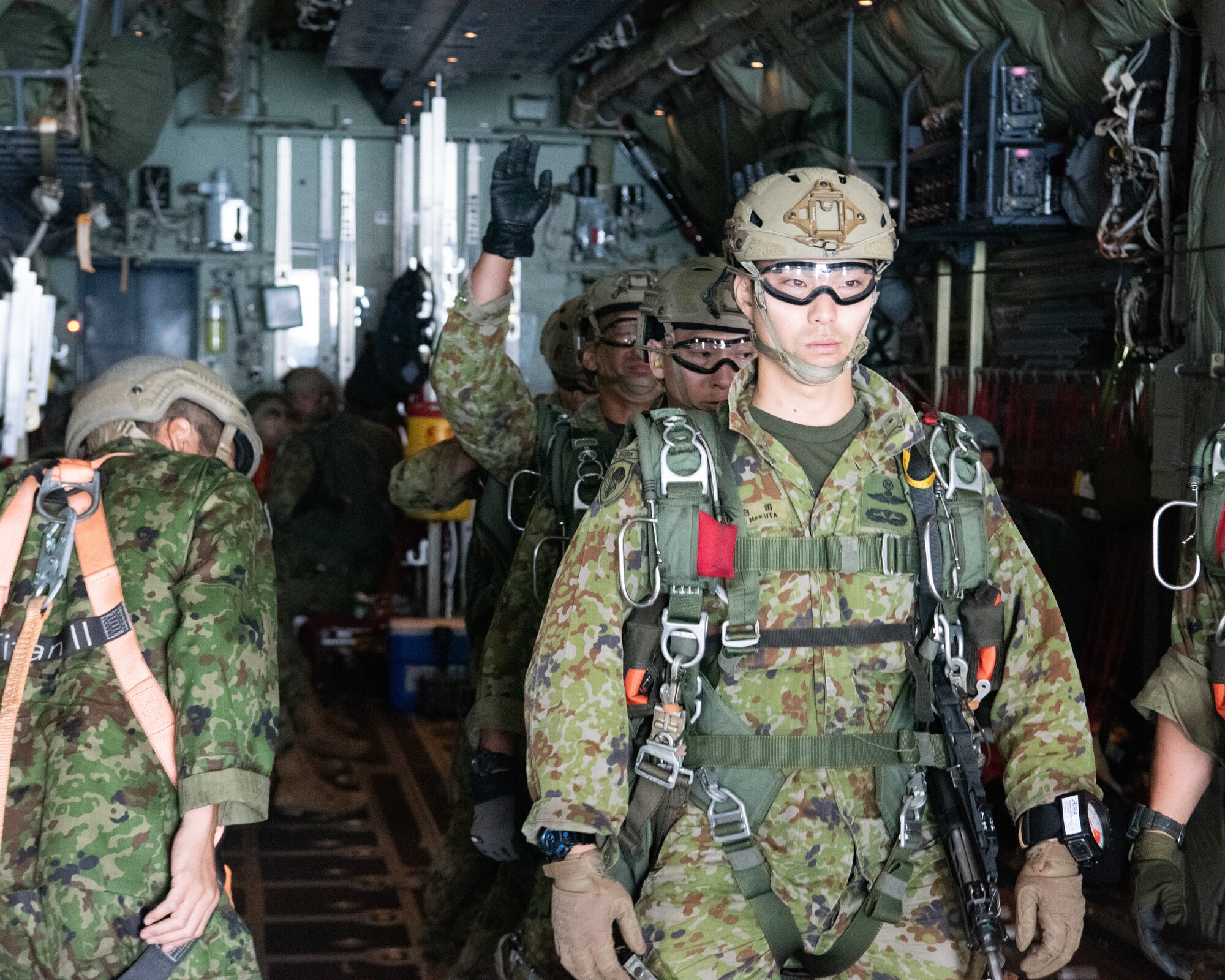 Japanese paratroopers form a line in the back of a large aircraft.