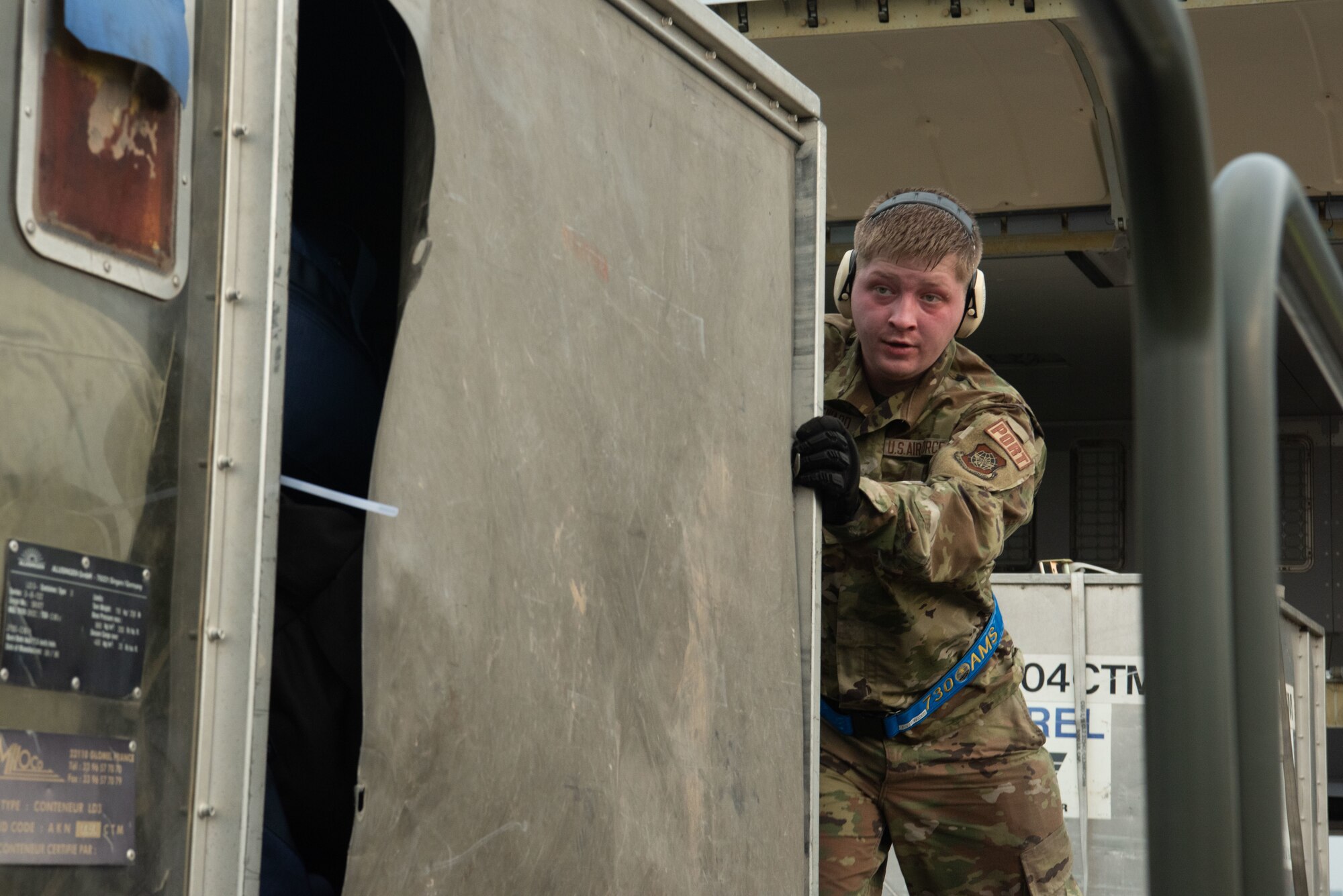 A U.S. Air Force Airman pushes a large container towards the camera.
