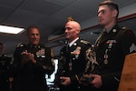 Command Sgt. Maj. John Raines, the command sergeant major of the Army National Guard, applauds after presenting trophies to U.S. Army Staff Sgt. Kirtley Finnell, center, a combat engineer with the 20th Special Forces Group, Alabama Army National Guard, and U.S. Army Sgt. Peter Fillion, an infantryman with C Troop, 2nd Squadron, 101st Cavalry Regiment, New York Army National Guard, after they were named the 2024 Army National Guard Noncommissioned Officer and Soldier of the Year during a ceremony in Burlington, Vermont, Aug. 8, 2024.