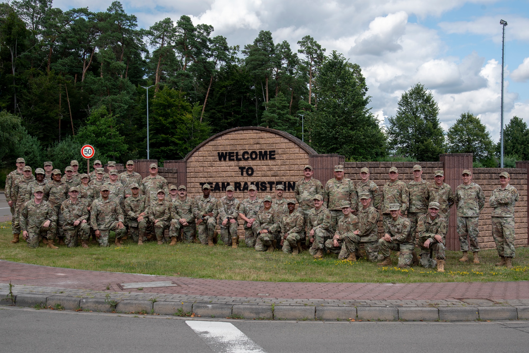 Members of the 134th Communications Squadron pose for a photo in front of welcome sign at Ramstein Air Base in Germany during annual training.