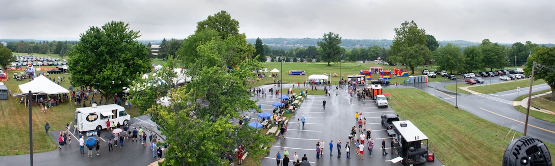 An aerial photo of tents, trees, food trucks and people gathering.