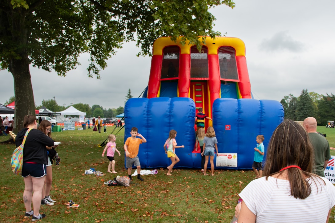Children climb on a blue, red and yellow inflatable slide.
