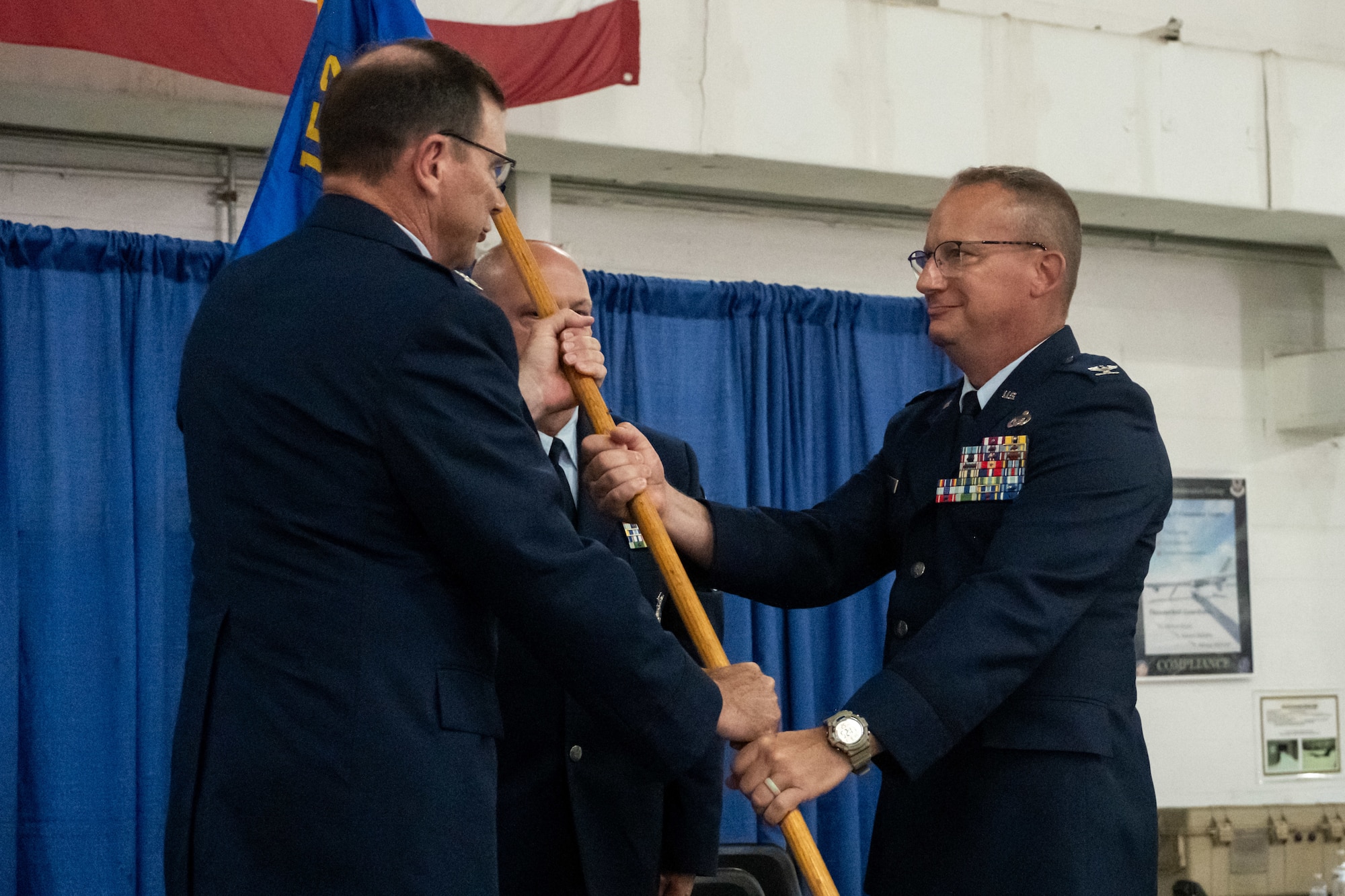 U.S. Air Force Col. John O'Connor, commander of the 174th Attack Wing, passes the 152nd Air Operations Group (AOG) guidon to incoming commander, Col. John Meili during a change of command ceremony for the 152nd AOG at Hancock Field Air National Guard Base, Aug. 03. During the ceremony, Meili assumed command of the group from outgoing commander, Col. Kevin St. John. (U.S. Air National Guard photo by Tech Sgt. Alexander Rector)