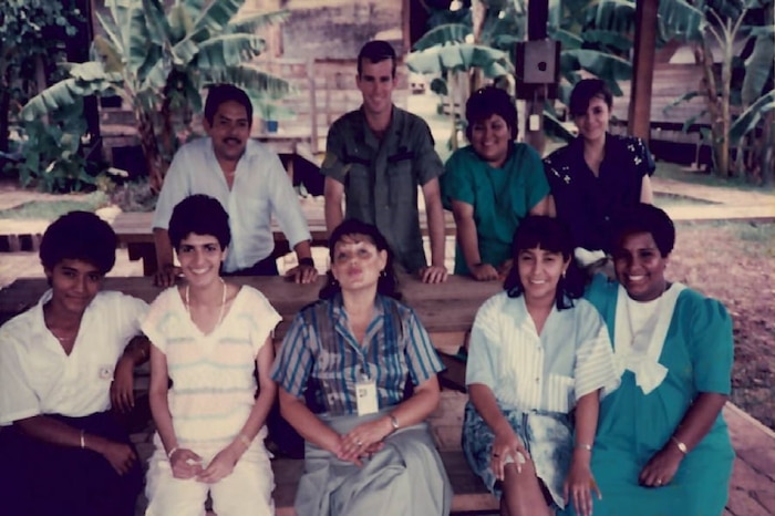 A photo of people at a picnic table posing for a photo.