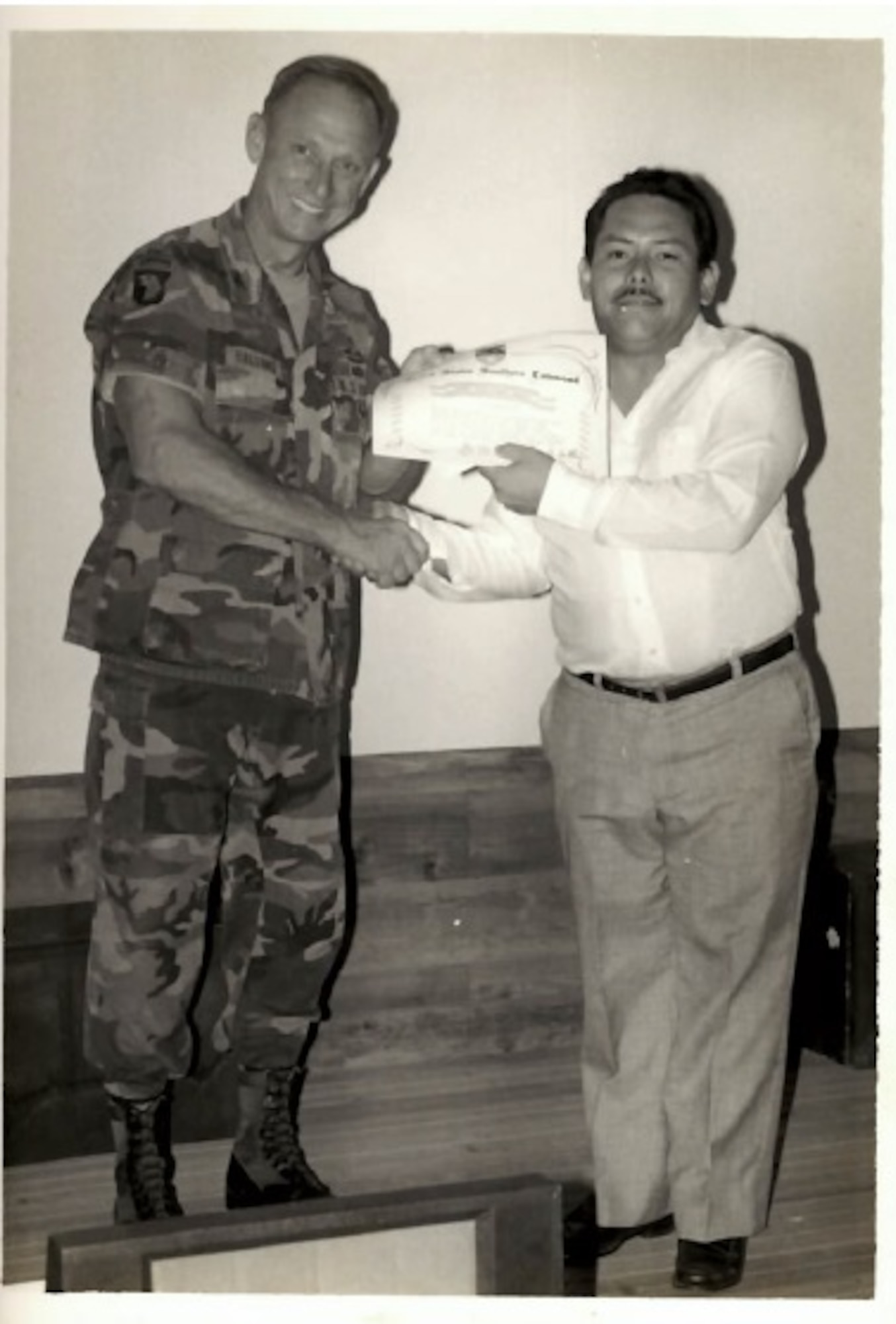A photo of a person holds an award with another person.