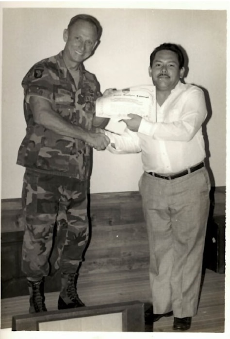 A photo of a person holds an award with another person.