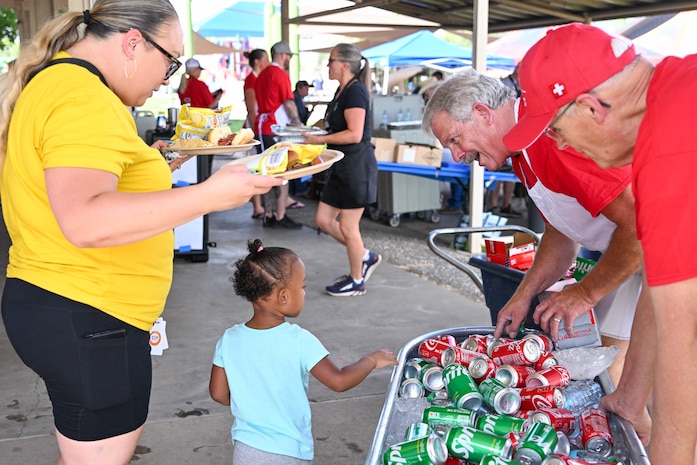 Two volunteers hand out drinks to a mother and child
