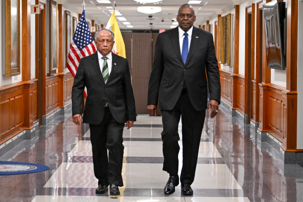 Two people in business attire walk together down a hallway.