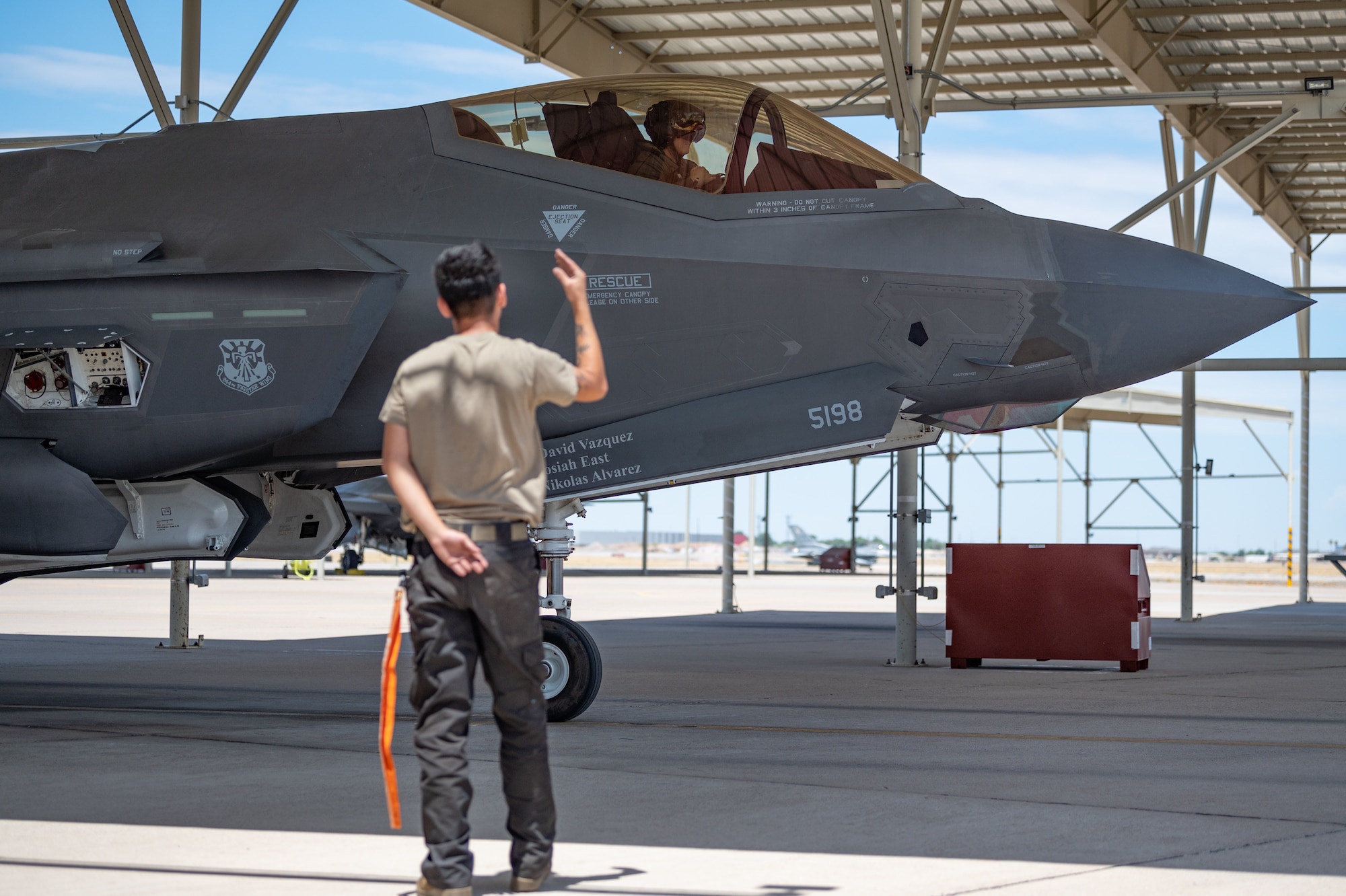Airman 1st Class Christian Dickinson, an active-duty crew chief with the 63rd Fighter Squadron, guides Reserve Citizen Airman Lt. Col. Christopher "Lube" Lowe, F-35 instructor pilot and 56th Operations Group deputy commander, through final checks during the approach and shutdown of his aircraft after completing his 1,000th flight hour in the F-35 Lightning II at Luke Air Force Base, Ariz., Aug. 9, 2024. This critical phase ensures the safe and secure conclusion of each flight, reflecting the meticulous teamwork between pilots and ground crews. (U.S. Air Force photo by Tech. Sgt. Tyler J. Bolken)