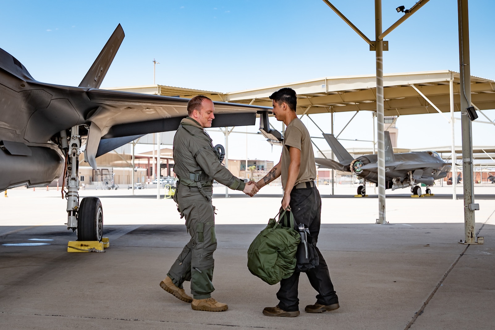 Reserve Citizen Airman Lt. Col. Christopher "Lube" Lowe, F-35 instructor pilot and 56th Operations Group deputy commander, shakes hands with Airman 1st Class Christian Dickinson, an active-duty crew chief with the 63rd Fighter Squadron, after completing his 1,000th flight hour in the F-35 Lightning II at Luke Air Force Base, Ariz., Aug. 9, 2024. The milestone flight underscores the teamwork between pilots and ground crews in the 944th Fighter Wing. (U.S. Air Force photo by Tech. Sgt. Tyler J. Bolken)