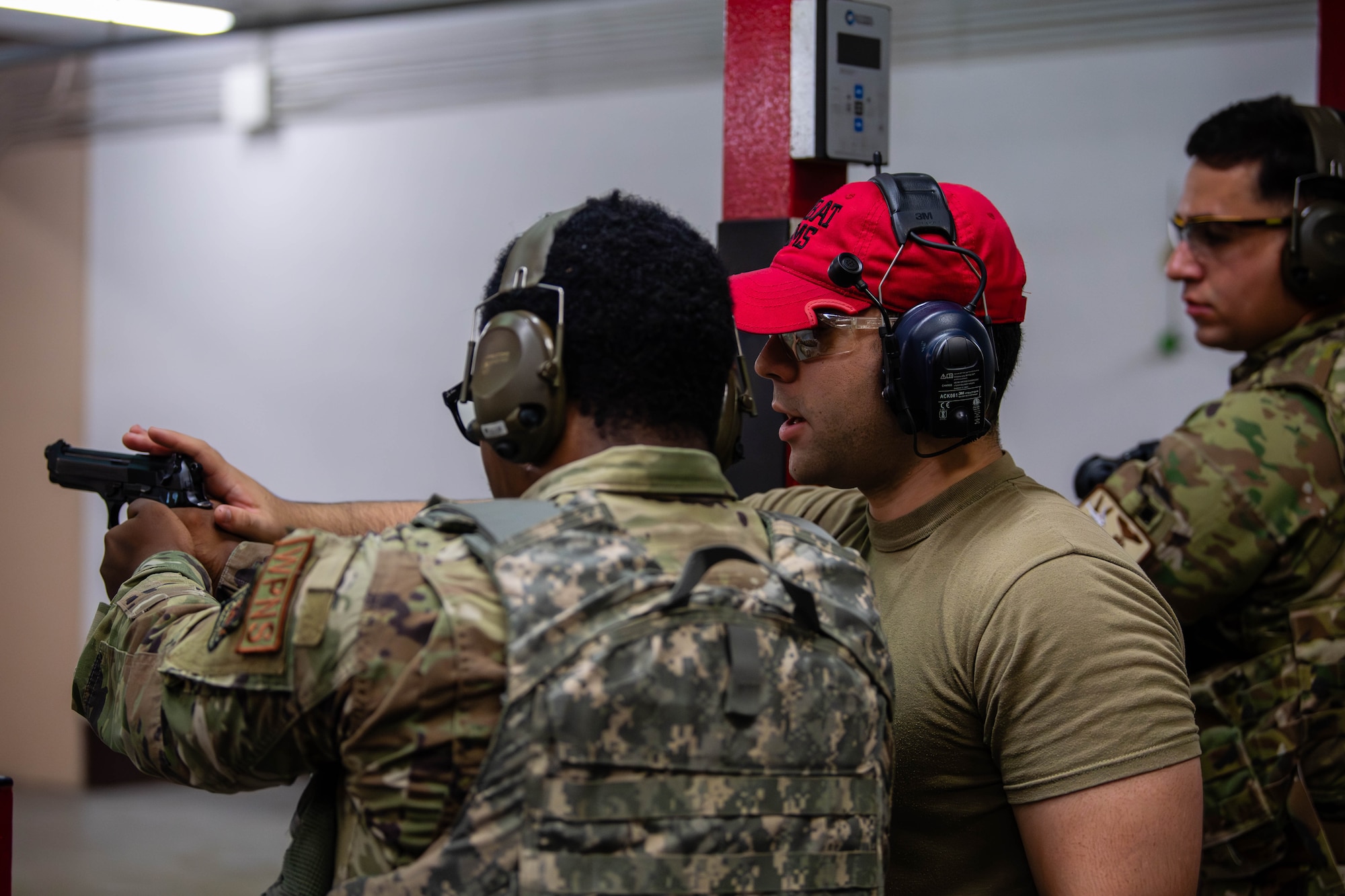 U.S. Air Force Airman Donovan Hall, 21st Special Operations Aircraft Maintenance Squadron weapons apprentice, is assisted by Senior Airman Ernest Crisson Betancourt, 374th Security Forces Squadron combat arms training and maintenance instructor, during an M9 pistol training course at Yokota Air Base, Japan.
