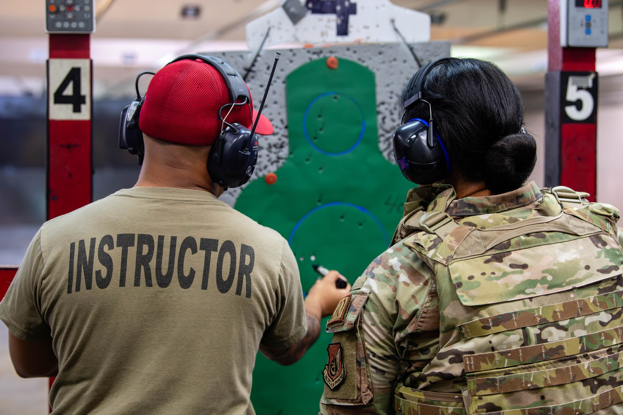 U.S. Air Force Tech. Sgt. Nathaniel Green, 374th Security Forces Squadron combat arms training and maintenance section chief, gives feedback to Maj. Melody Chong, 374th Logistics Readiness Squadron director of operations, during an M9 pistol training course at Yokota Air Base, Japan.