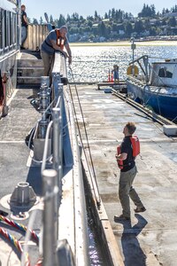 Michael Richardson, diving operations supervisor, Code 760, Regional Dive Division, and Cody Kmecheck, boat tender, Code 740, Riggers, tie up the Dive Locker's new dive boat after arriving at the Port Orchard, Washington, Marina Dock, Aug. 1, 2024. (U.S. Navy photo by Jeb Fach)