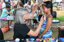 A child getting her face painted by an artist