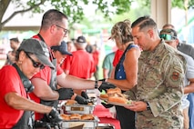 People are handed hamburgers at a picnic