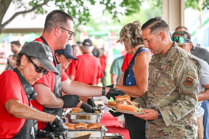 People are handed hamburgers at a picnic