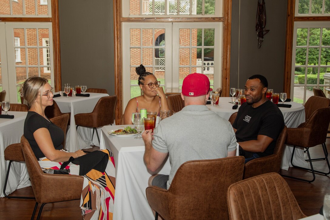 Four people sitting down eating dinner.