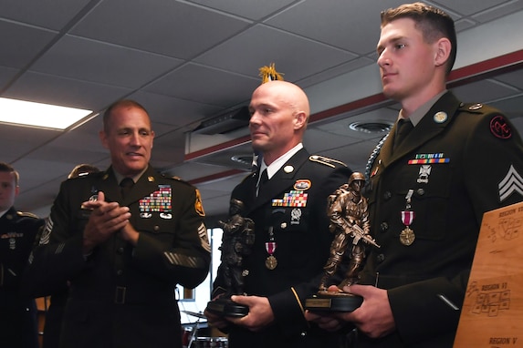 Two officers hold awards while others clap.