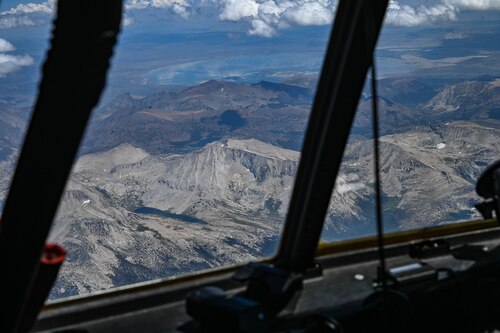 A desert landscape is seen out the window of a flying C-130J Super Hercules aircraft.