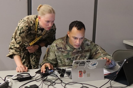 A member of the Finnish Defense Forces collaborates with a Virginia National Guard cyber operator July 15, 2024, during Cyber Fortress 3.0 at the State Military Reservation, Virginia Beach.