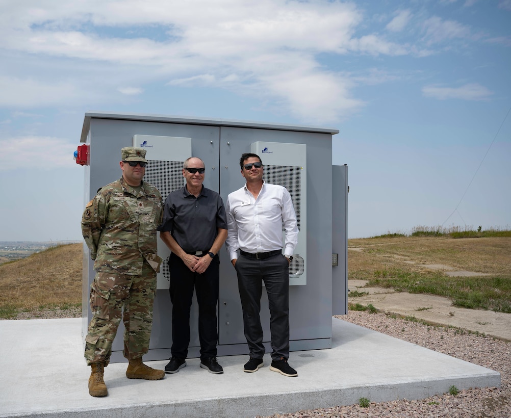 U.S. Air Force Maj. Michael Glynn, 28th Logistics Readiness Squadron commander (left), Richard Johnson, CEO and manager, West River Electric Association (center), and Robert Raker, Manager of Public Relations, West River Electric (right), pose for a photo in front of a Battery Energy Storage System in Box Elder, S.D., 22 July, 2024. Ellsworth Air Force Base worked with West River Electric Association (WREA), SAFT/GoElectric, the National Rural Electric Cooperative Association (NRECA), Pacific Northwest National Lab, and Sandia National Laboratories using a Department of Energy (DOE) grant to action the project. (U.S. Air Force photo by Senior Airman Josephine Pepin)