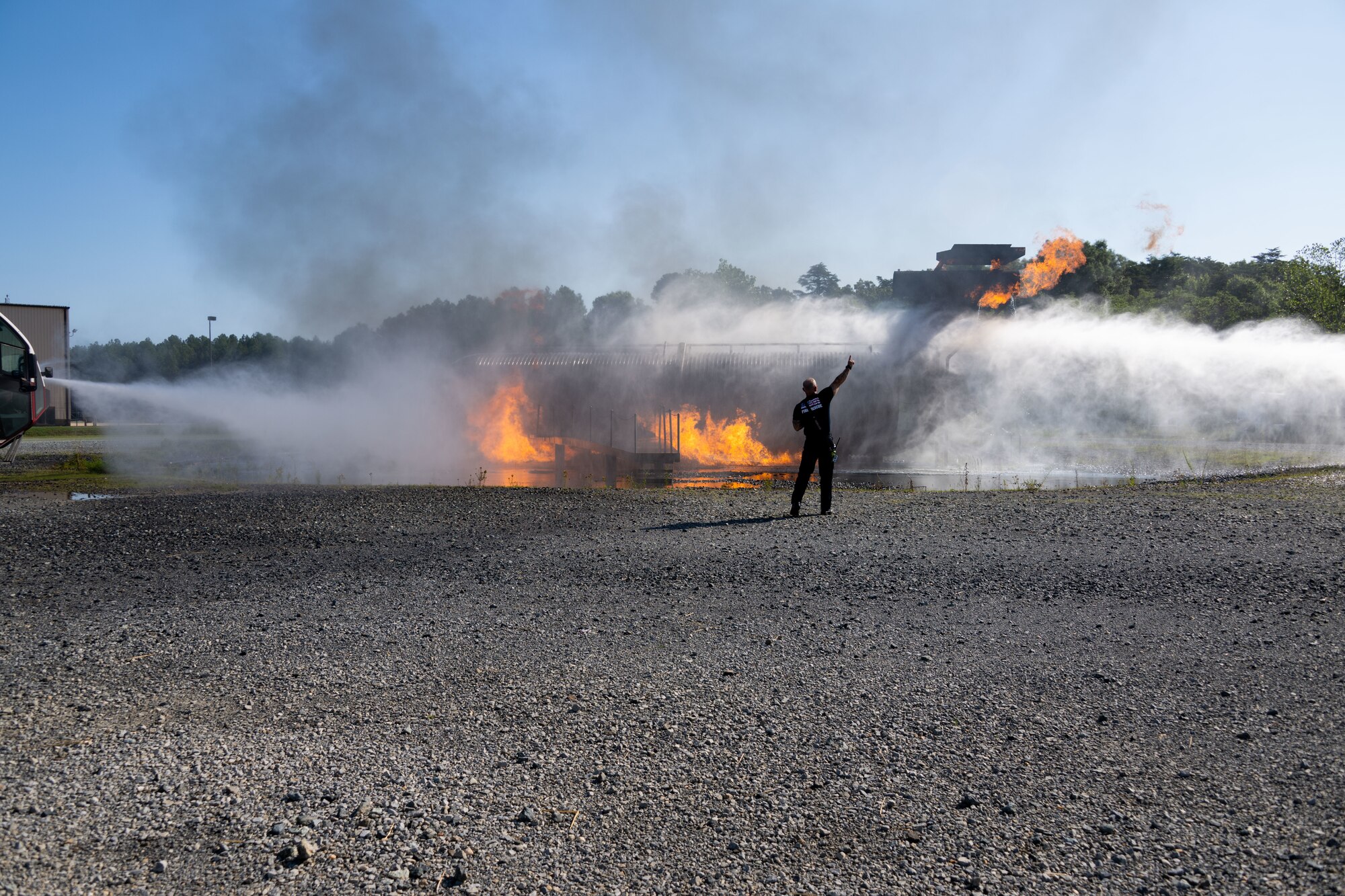 Fireman stands while fire trucks spray water