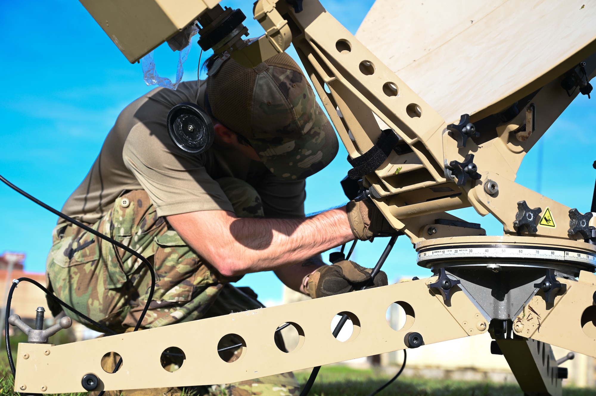 An Airman connects a cable to a satellite dish.