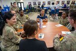 Kelli Williams, DRIVE (Develop, Redistribute, Improve, Vault, Expose) program manager, engages with 737th Training Group trainees around a table at the DRIVE Joint Forces Employment Fast Track event on June 28, 2024, at the Pfingston Reception Center on Joint Base San Antonio-Lackland.
