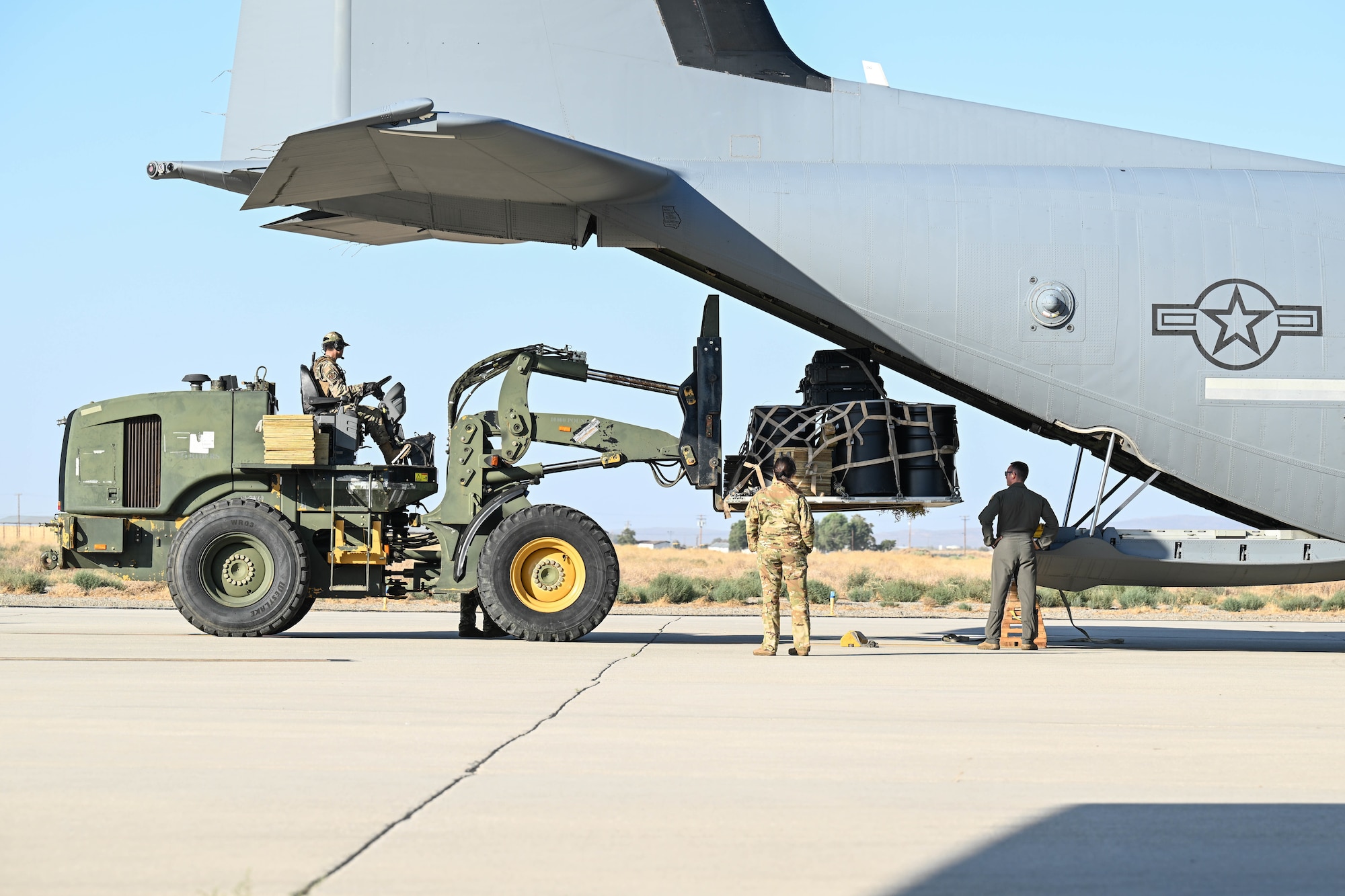 A forklift lifts and loads cargo into the back of an aircraft.