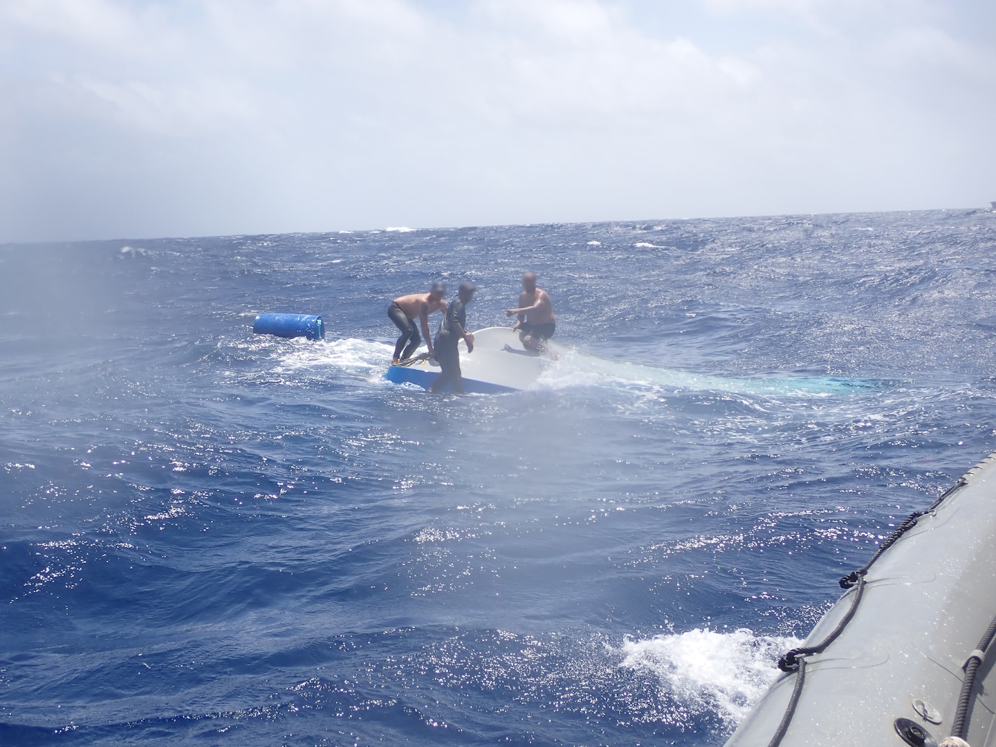 Suspected drug smugglers standing on top of a sinking vessel approximately 90 miles south of Haiti on July 24, 2024. The USS St. Louis launched a small boat crew to rescue the suspected smugglers after their vessel capsized. (Courtesy photo)