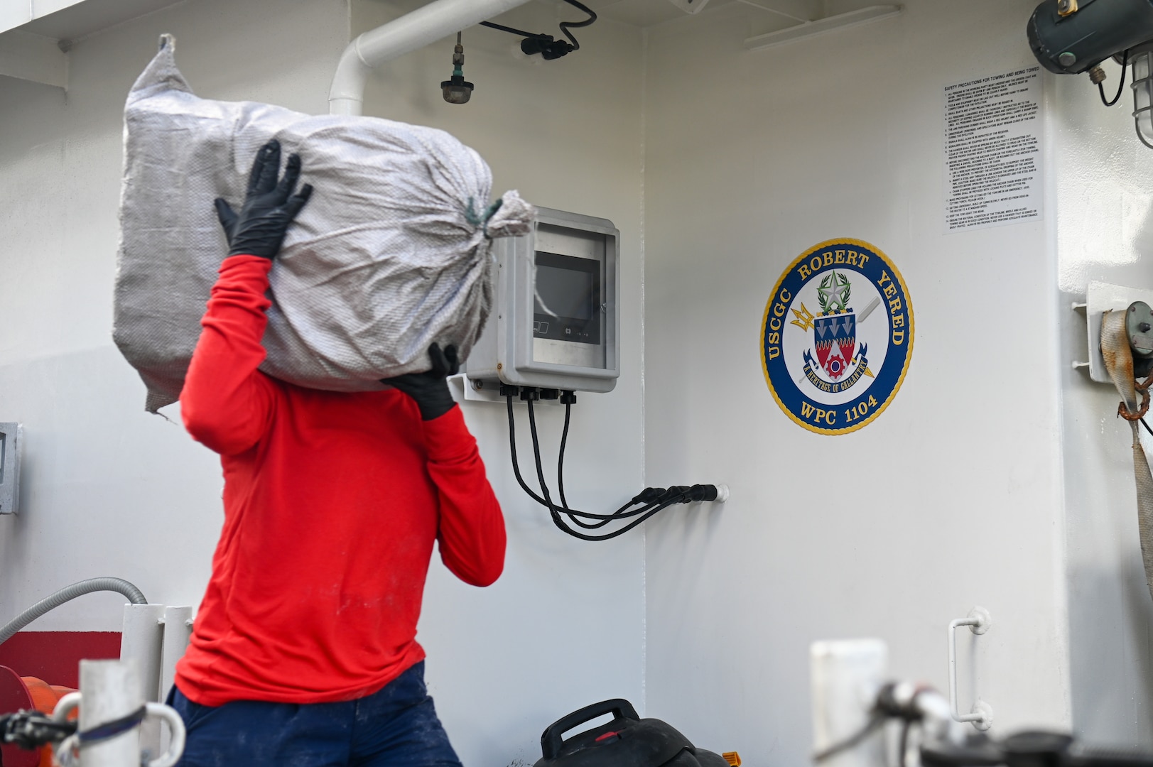 A crew member of the Coast Guard Cutter Robert Yered carries a bale of cocaine to shore for destruction at Base Miami Beach on August 14, 2024. Once ashore custody of interdicted narcotics are transferred to partner agencies. (U.S. Coast Guard photo by Petty Officer 3rd Class Nicholas Strasburg)