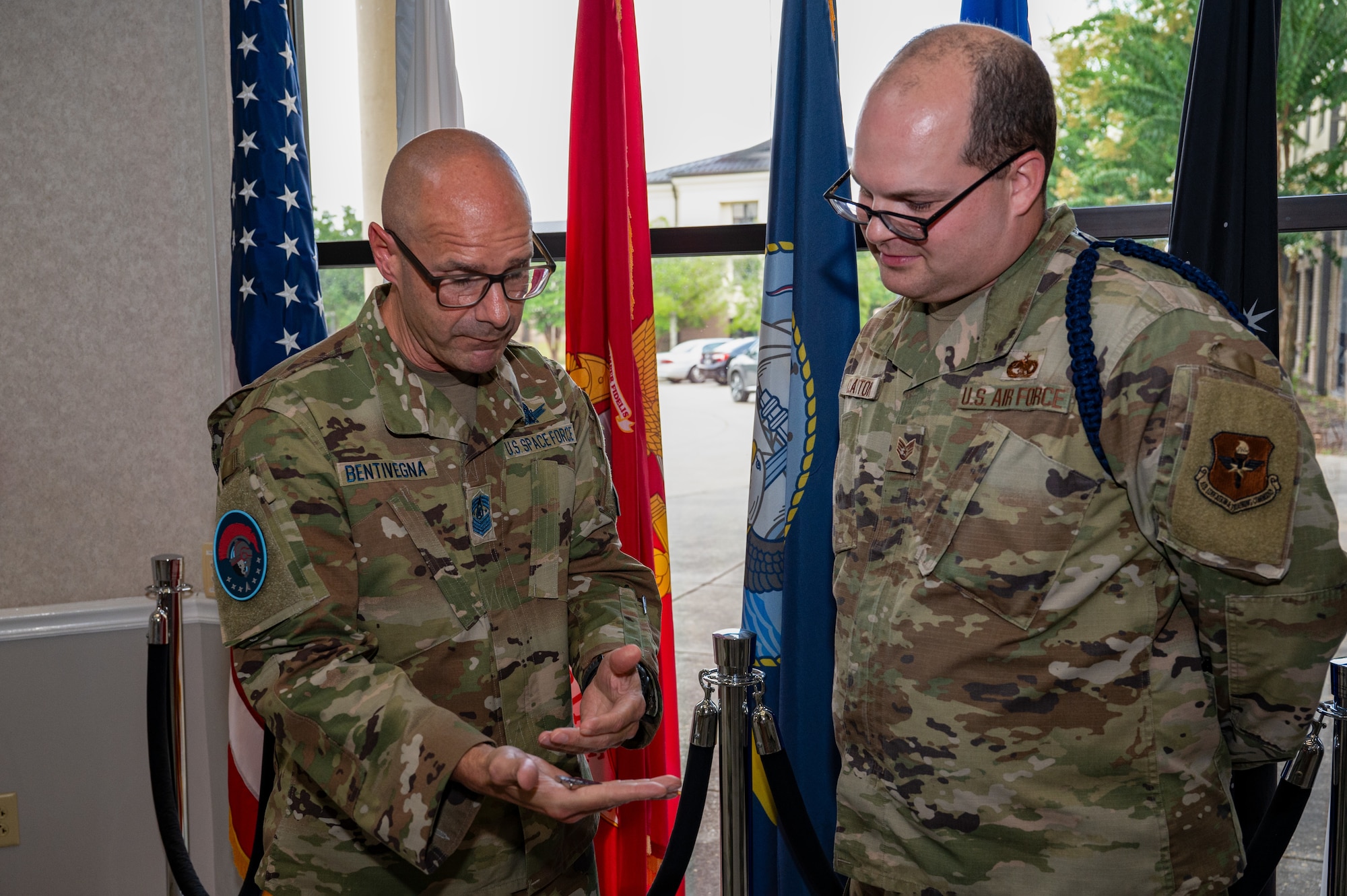 Chief Master Sergeant of the Space Force John F. Bentivegna describes the meaning behind his coin to Staff Sgt. Daniel Clayton, 338th Training Squadron military training leader, at Keesler Air Force Base, Mississippi, Aug. 9, 2024.