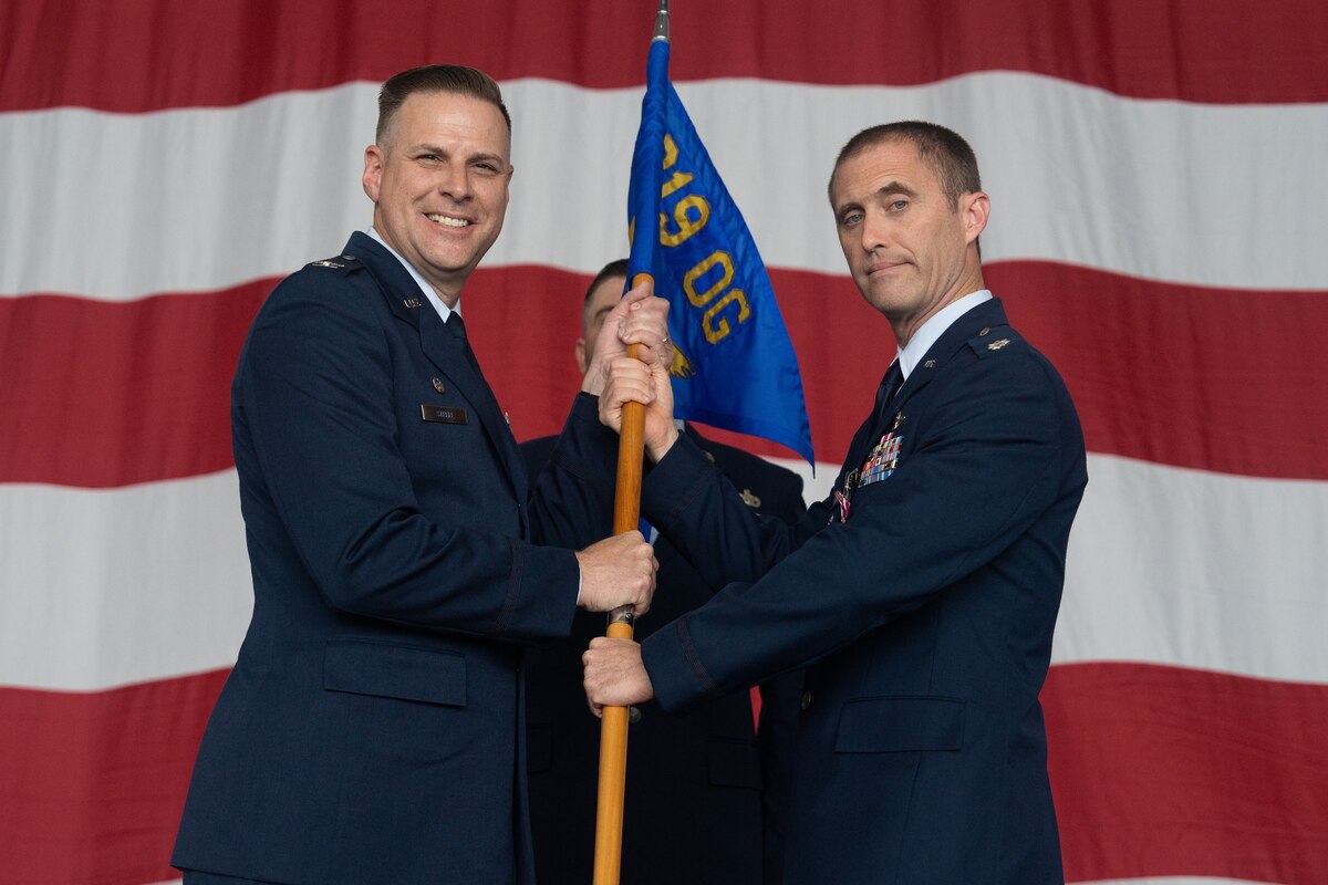 Two Airmen hold a guidon during a ceremony