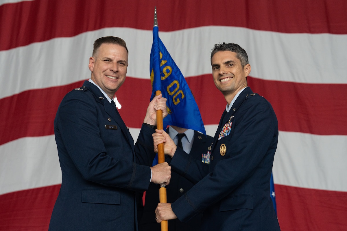 Two Airmen hold a guidon during a ceremony