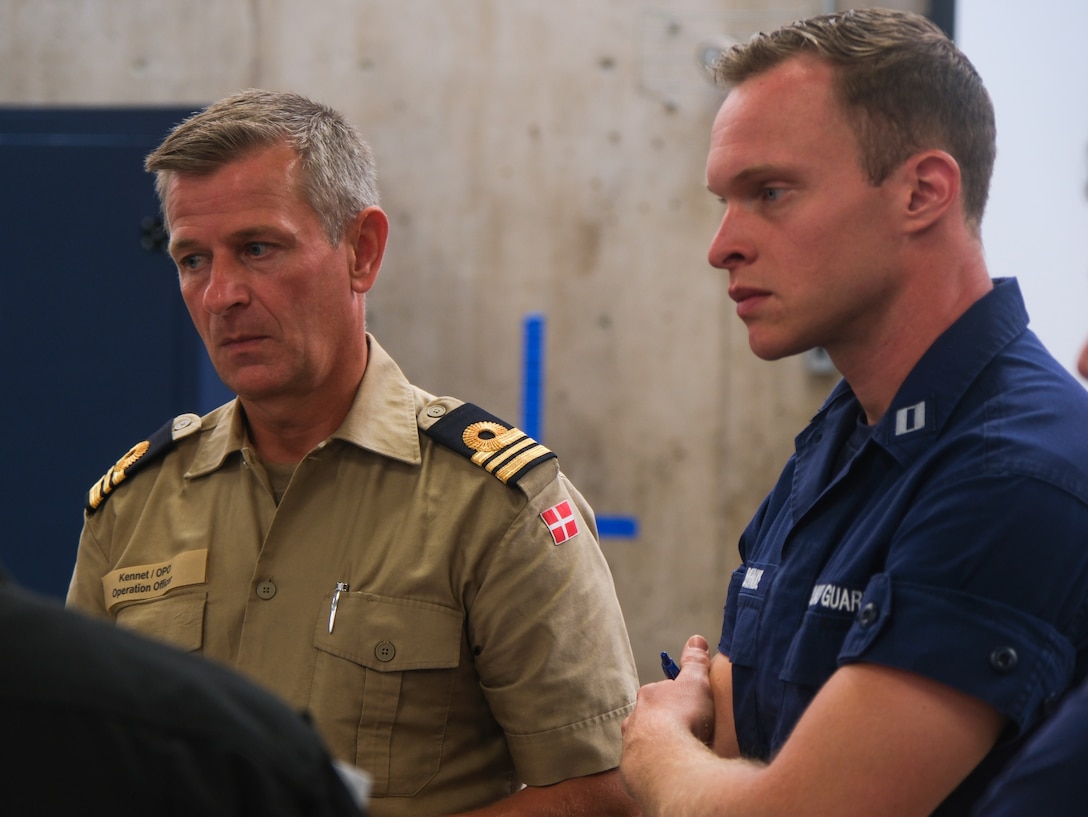 U.S. Coast Guard Lt. Jonathan Behnke, operations officer of Coast Guard Cutter Northland (WMEC 904), and Royal Danish navy Lt. Capt. Kennet Pedersen, operations officer of HDMS Lauge Koch (P 572), take part in the pre-sail conference for Operation Nanook in Halifax, Nova Scotia on Aug. 12, 2024. The Coast Guard partners with international allies to ensure the safety and security of the Arctic region. (U.S. Coast Guard photo by Petty Officer 3rd Class Anthony Randisi)