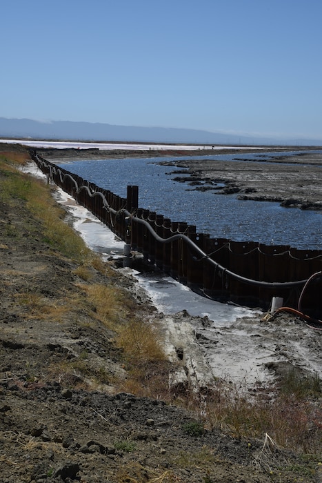 A metal wall separates water from land.