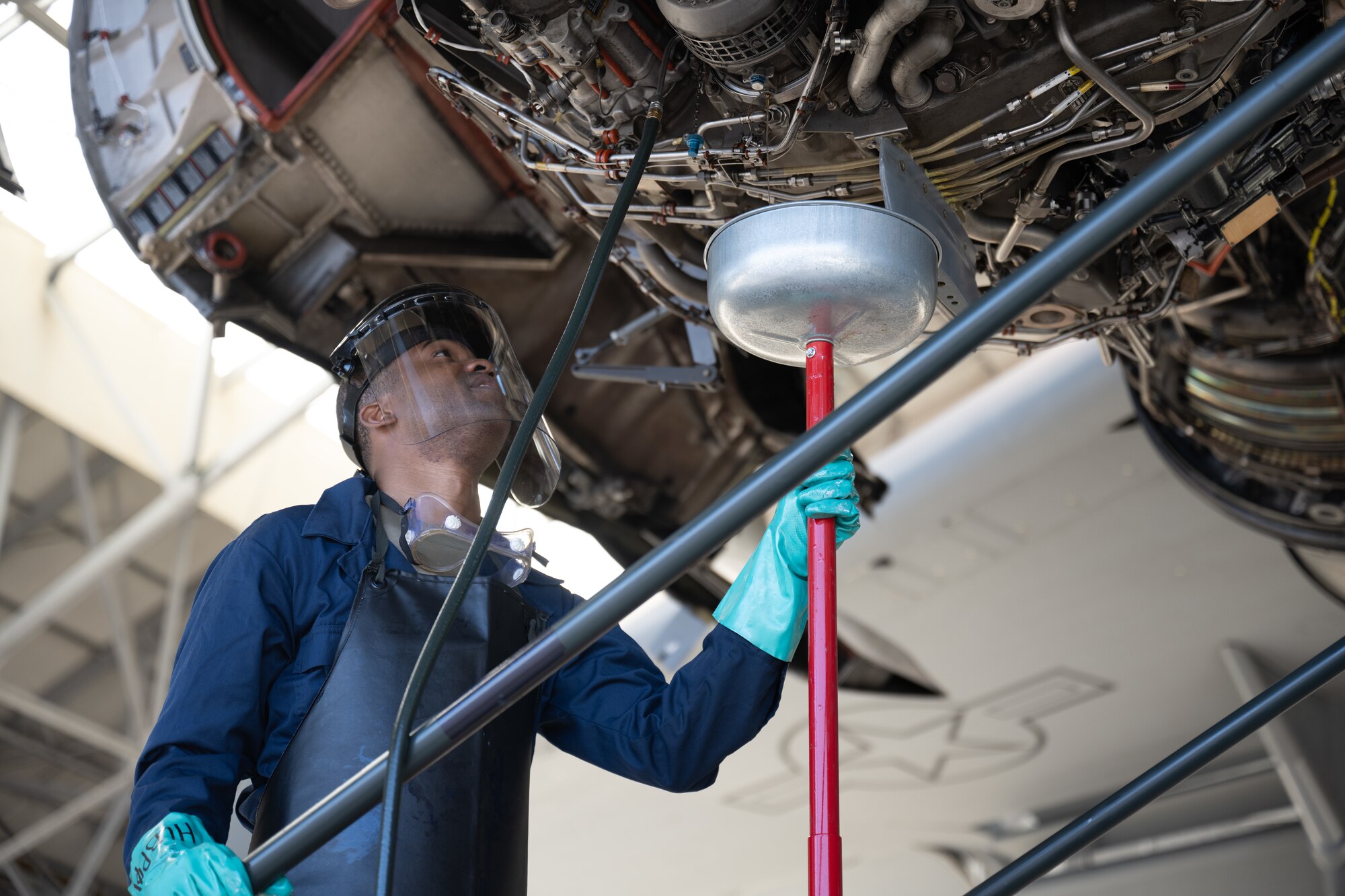 Airman collects oil from an aircraft engine.
