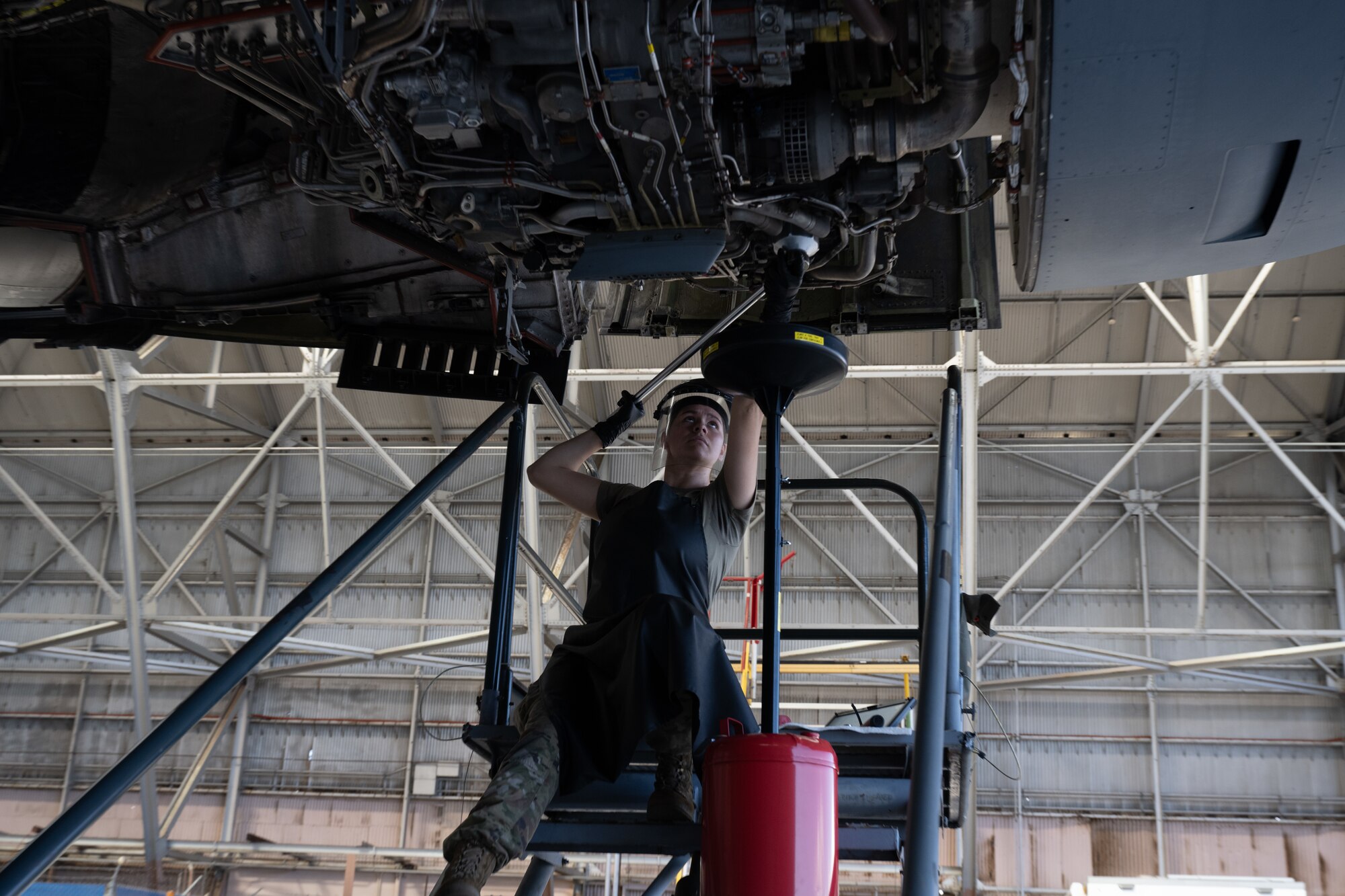 Airman performs maintenance on aircraft engine.