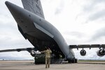 A U.S. Air National Guardsman with 446th Airlift Wing and a Royal Australian Airforce Airman with 24th Squadron guide a U.S. Marine Corps LAV-25 Light Armored Vehicle.