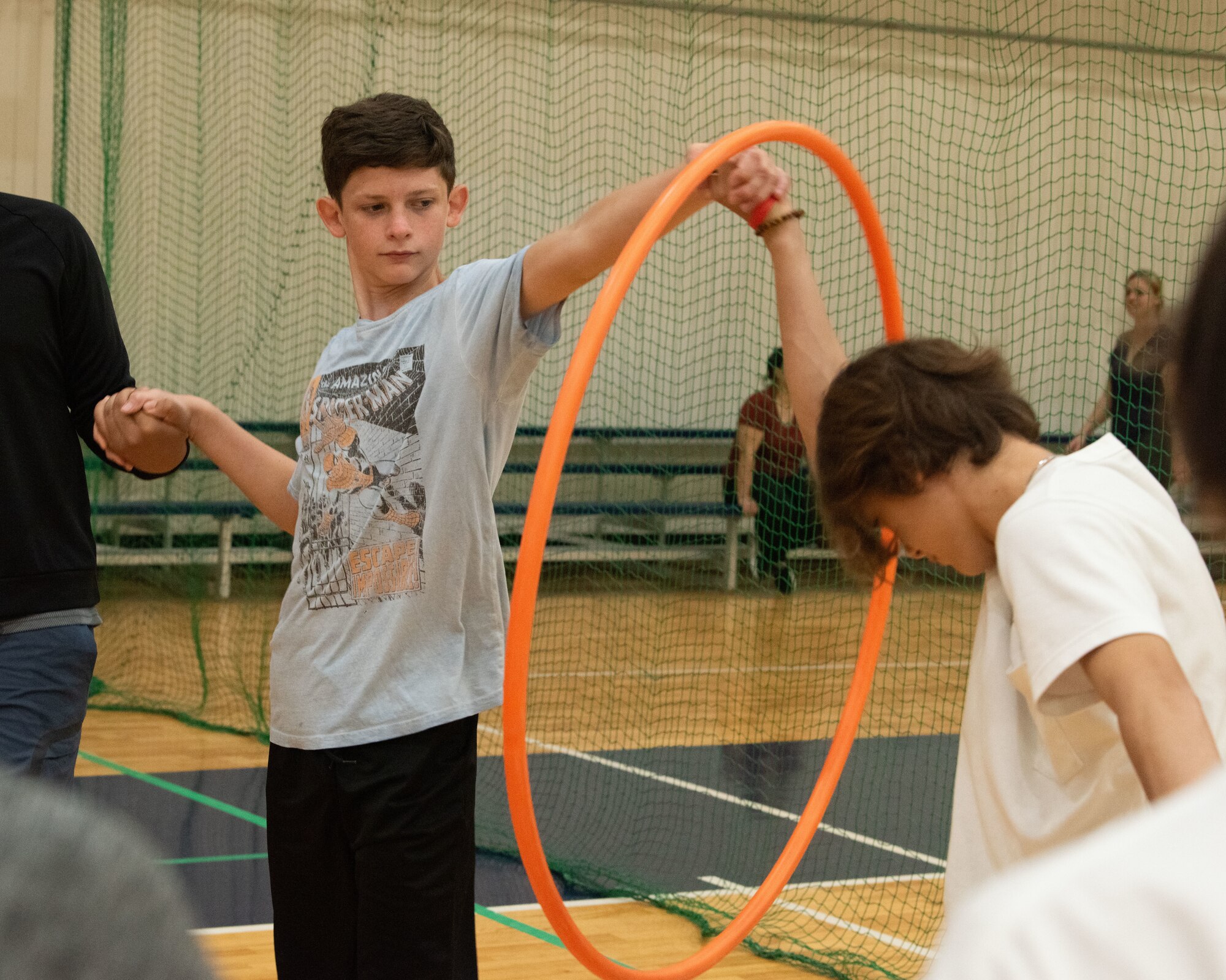 Children pass through a hula hoop while holding hands during a team-building activity.