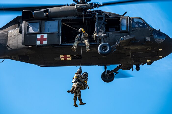 Photo of Airmen in a Black Hawk helicopter practicing hoisting rescue techniques with U.S. Air Force medical personnel
