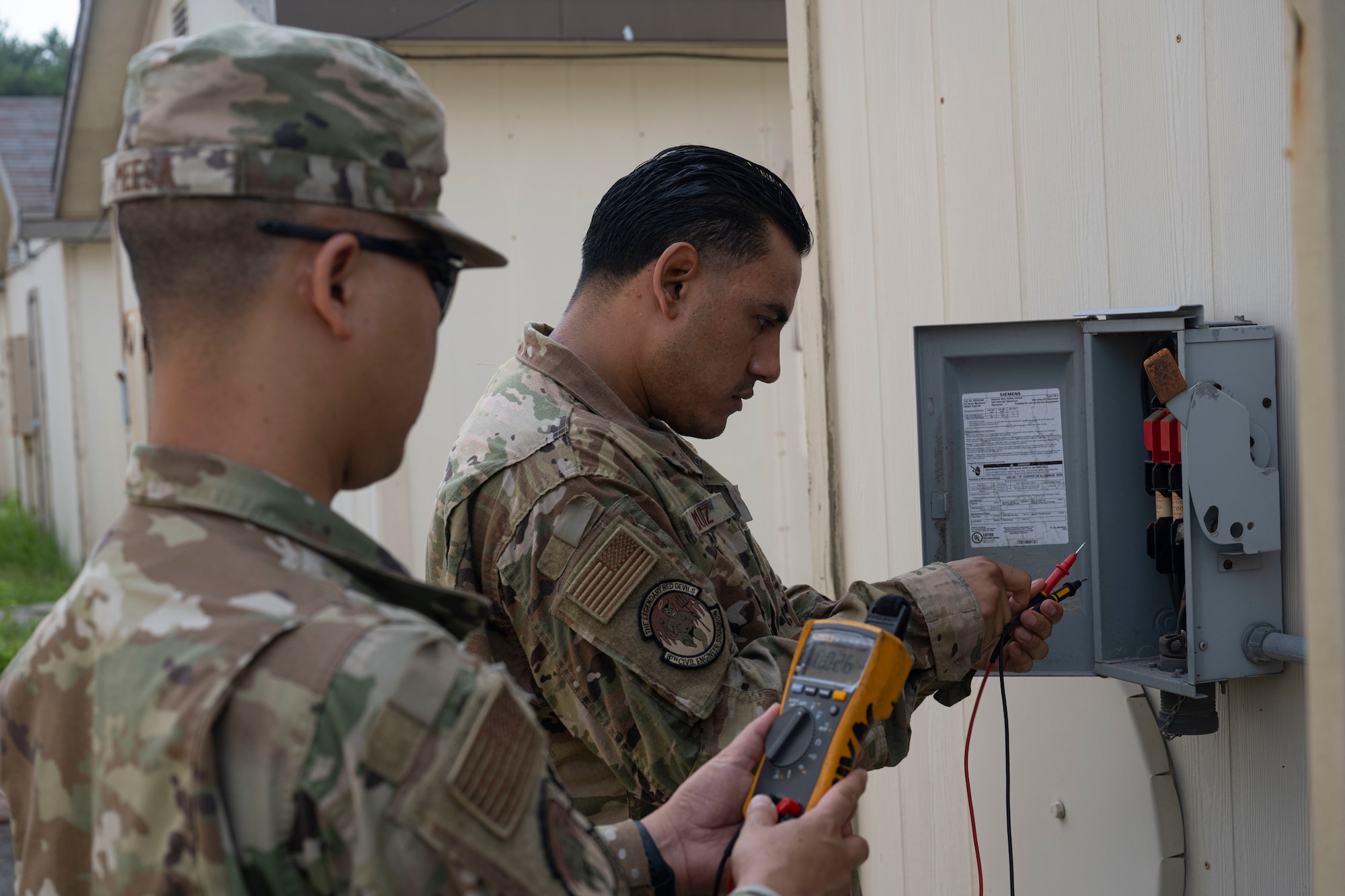 Senior Airman Intorn Messa, left, and U.S. Air Force Staff Sgt. Javier Ruiz, right, 8th Civil Engineer Squadron heating ventilation and air conditioning journeymen, test the fuses of a building at Kunsan Air Base, Republic of Korea.