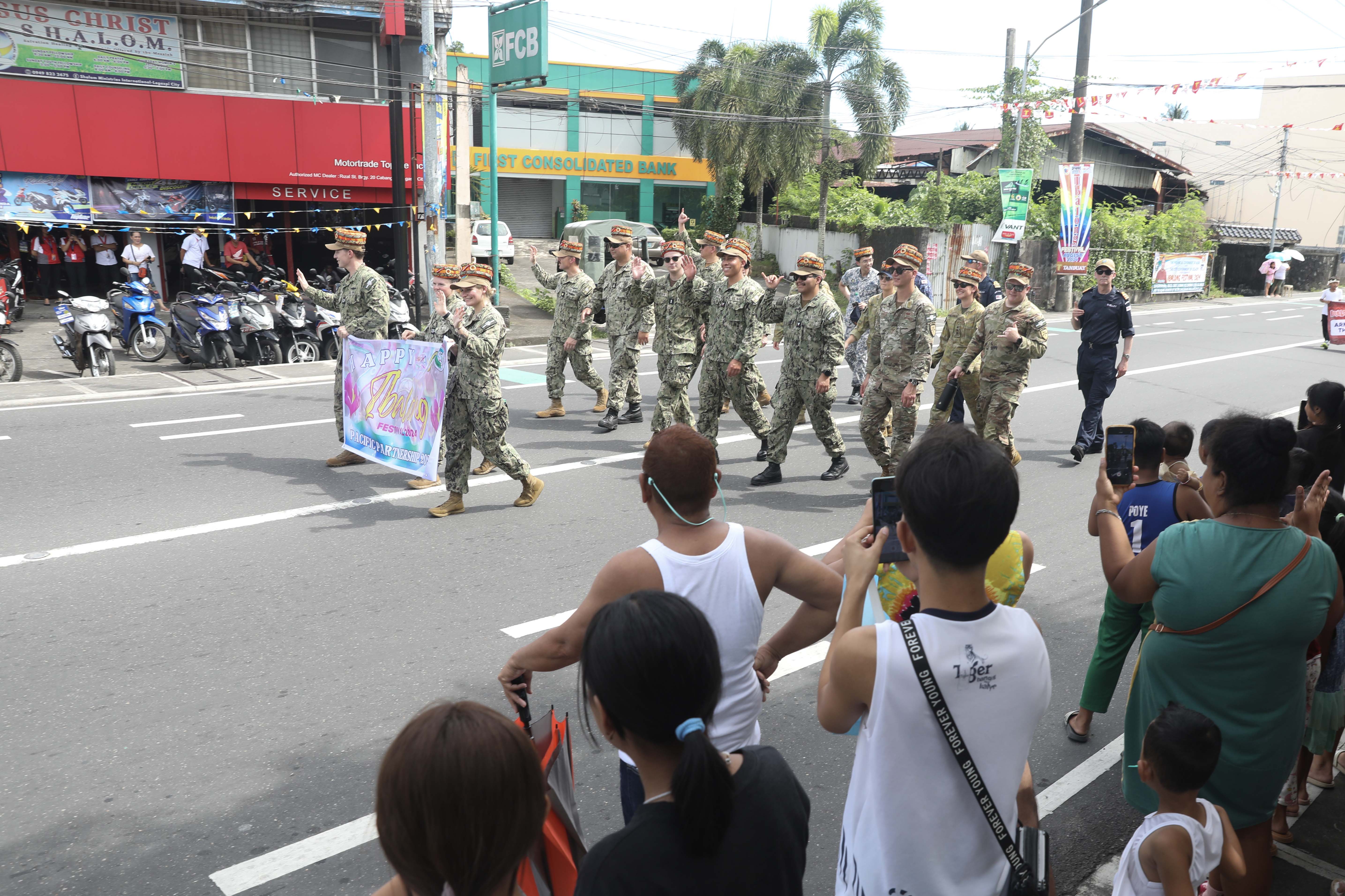 LEGAZPI, Philippines (Aug. 9, 2024) – Pacific Partnership 2024-2 service members wave to the crowd while participating in the Ibalong festival parade in Legazpi, Philippines, Aug. 9, 2024. A festival depicting the Bicol region’s early beginnings as portrayed by the characters in the epic – IBALONG.  Now in its 20th iteration, the Pacific Partnership series is the largest annual multinational humanitarian assistance and disaster relief preparedness mission conducted in the Indo-Pacific. Pacific Partnership works collaboratively with host and partner nations to enhance regional interoperability and disaster response capabilities, increase security and stability in the region, and foster new and enduring friendships in the Indo-Pacific. (U.S. Navy photo by Mass Communication Specialist 1st Class Ryan D. McLearnon/Released)