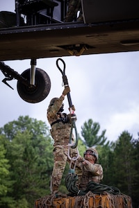 Oklahoma Army National Guard Spc. Michael Champion, a combat medic assigned to headquarters battery, 1st Battalion, 160th Field Artillery Regiment, 45th Infantry Brigade Combat Team, hooks a cargo load of ammo to a UH-60 Black Hawk during emergency airlift resupply training at Exercise Northern Strike 2024, Camp Grayling, Michigan, Aug. 11, 2024.