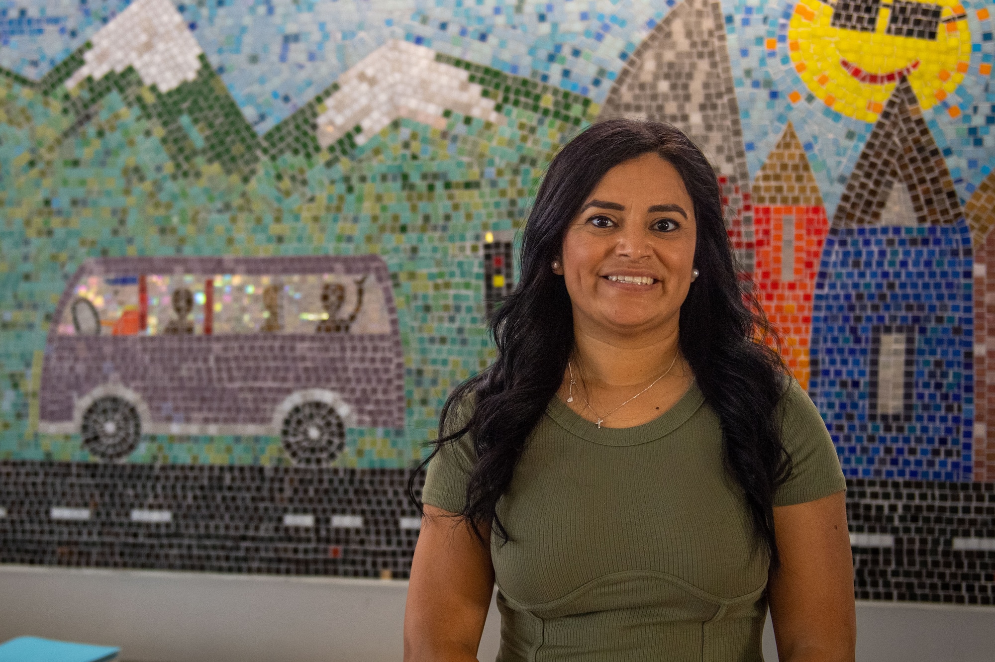 A woman stands in front of a mosaic