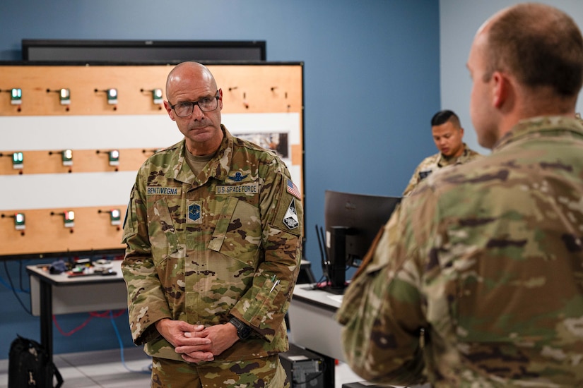 A military officer stands and listens to a service member talk.