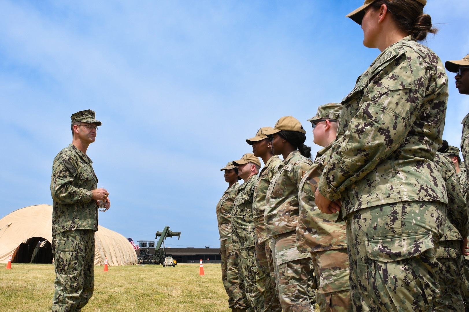 A group of military personnel dressed in camouflage talking outside